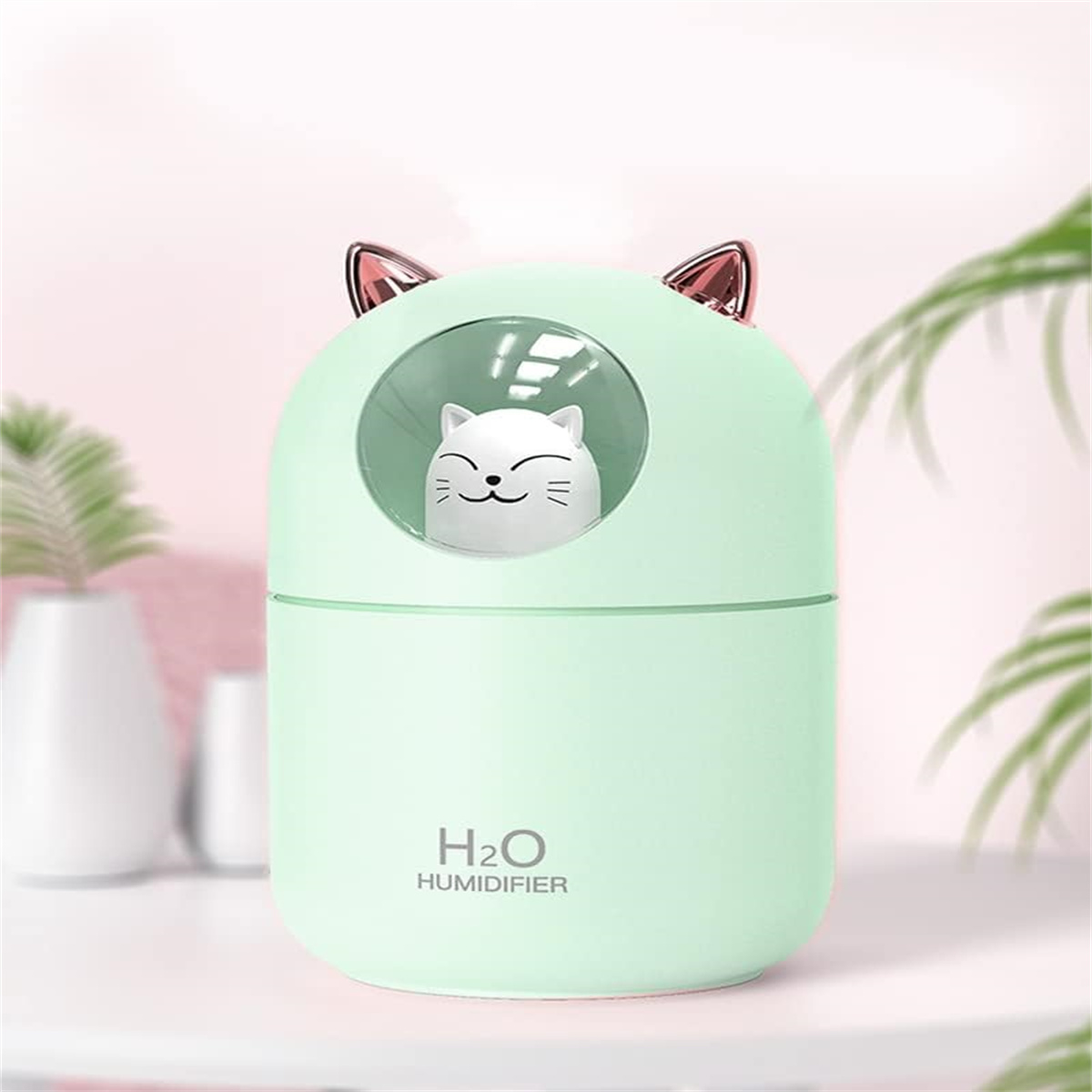 Ein grüner katzenförmiger Luftbefeuchter mit Katzenohren. Eine kleine Katzenfigur ist innen. H2O-Text.
