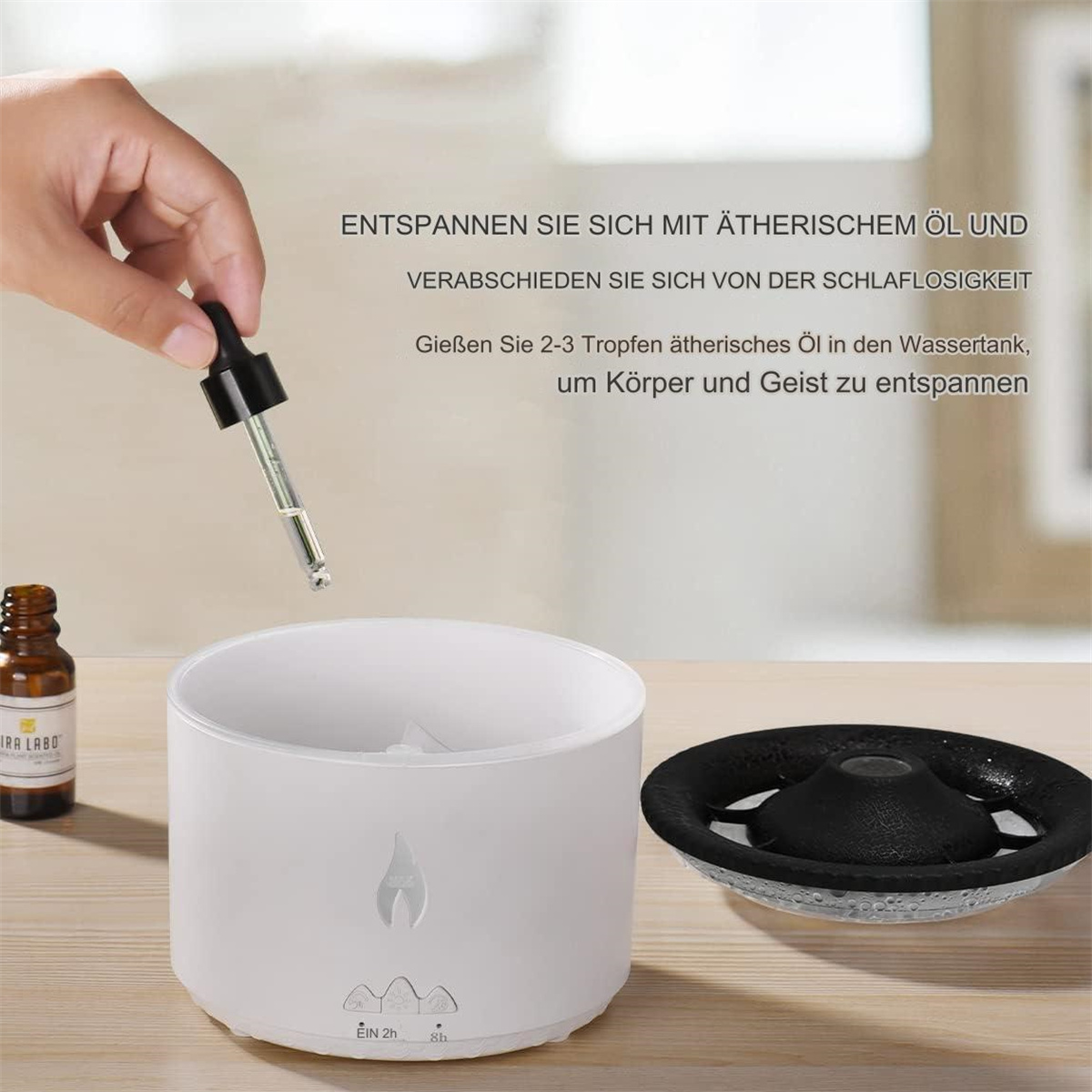 Person gießt ätherisches Öl in einen weißen Diffusor. Eine kleine Flasche und schwarzer Diffusor sind sichtbar.