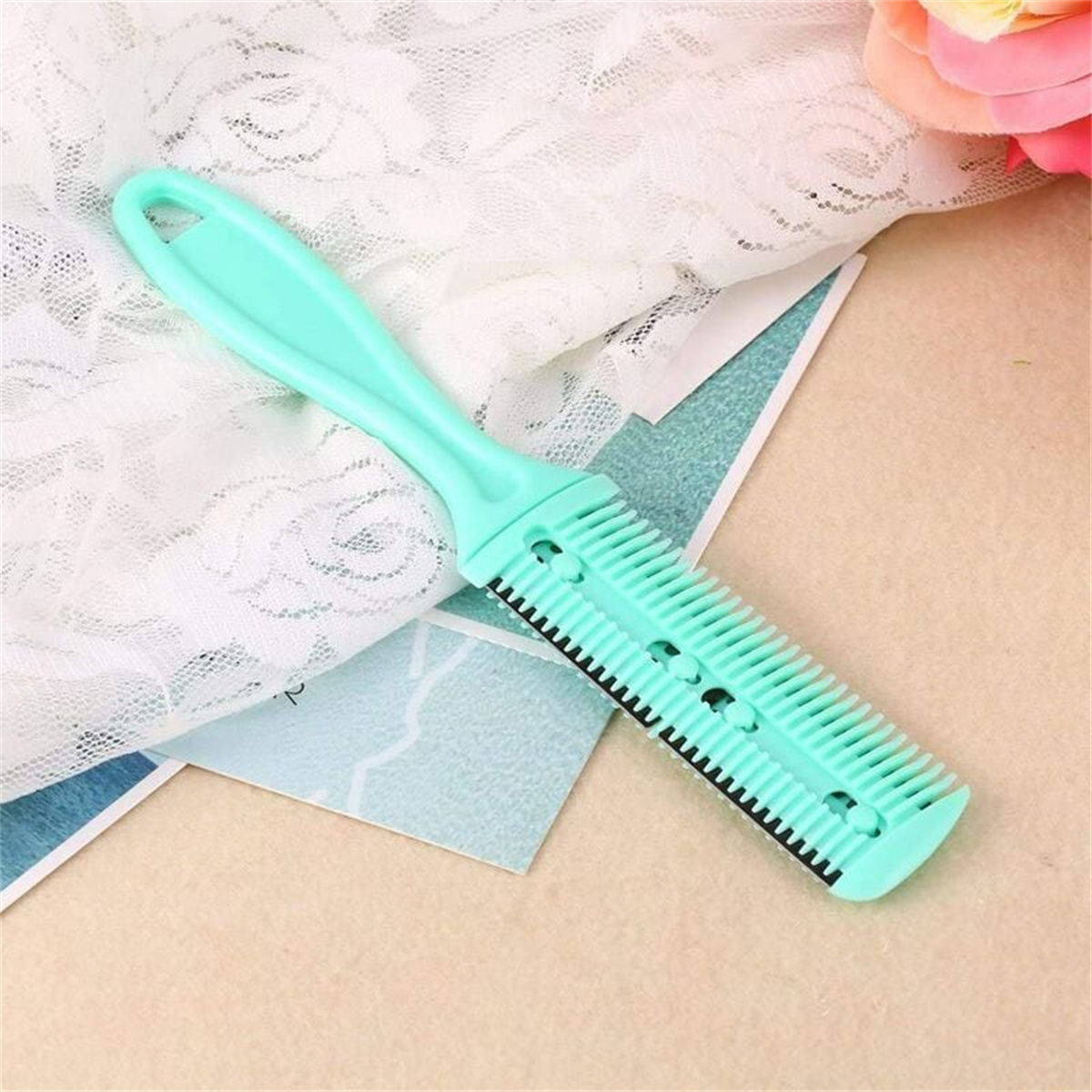 Ein hellgrüner Haarschneidekamm mit Griff. Er liegt auf einer weißen Spitze und einem blauen Papier.