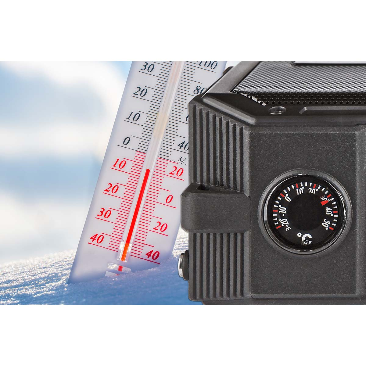 Thermometer und Kompass neben Schnee. Klarer Himmel im Hintergrund.