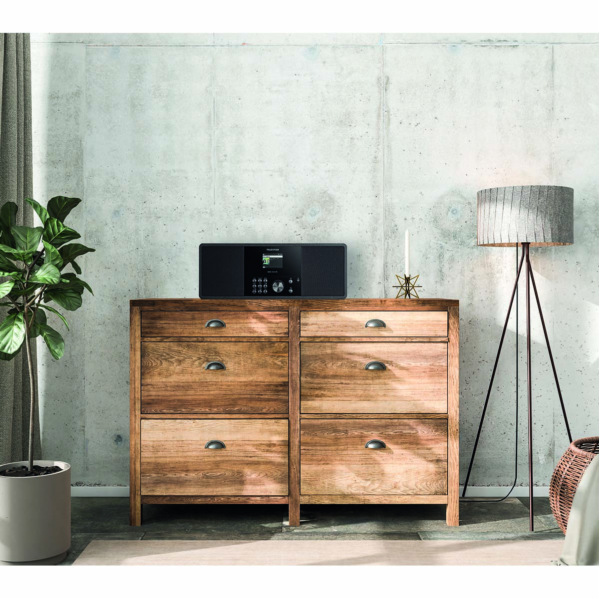 Radio na drewnianej szafce, z rośliną, świecą i lampą podłogową w tle.