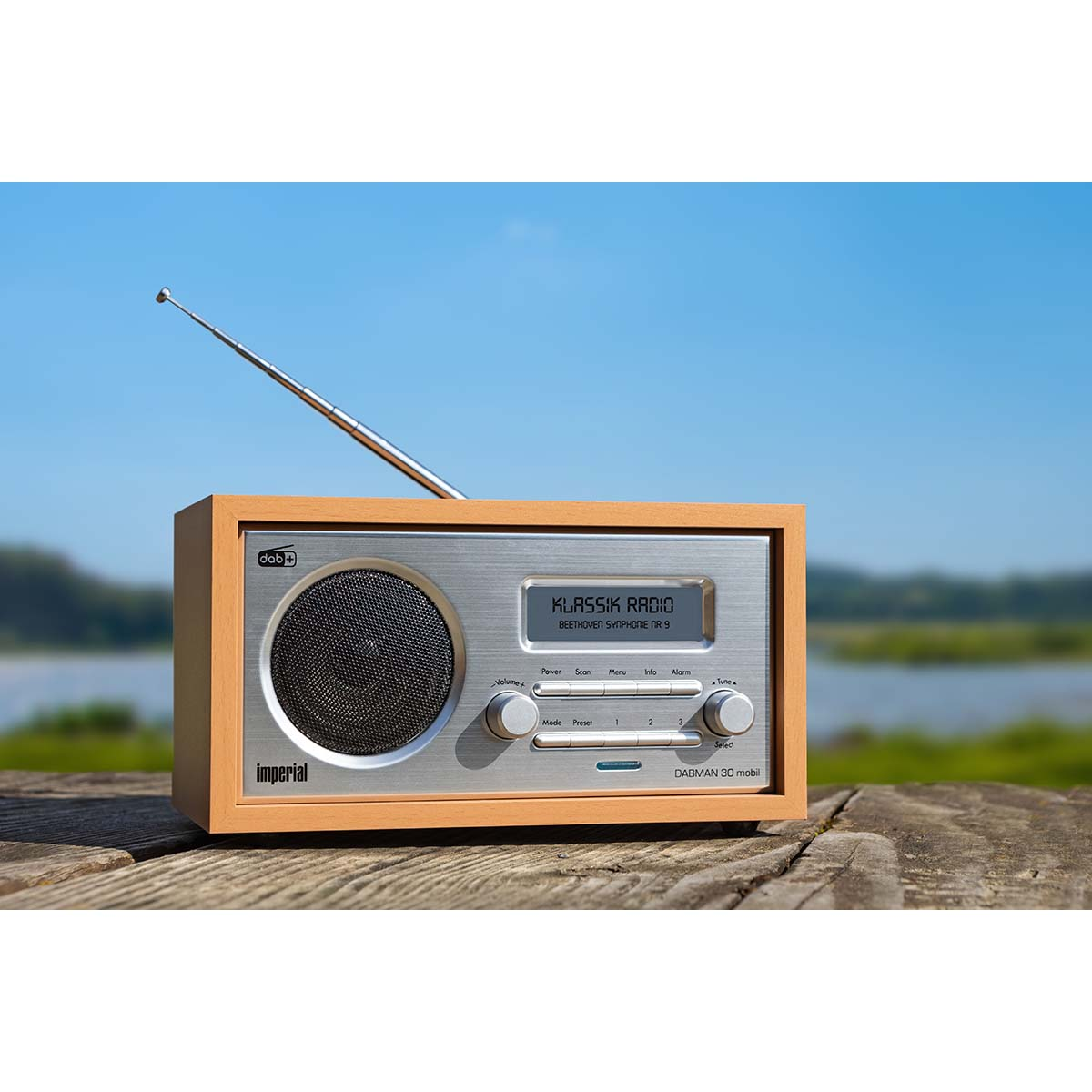 Houten radio op een houten tafel, een blauwe lucht op de achtergrond. De radio zegt 'KLASSIK RADIO'.