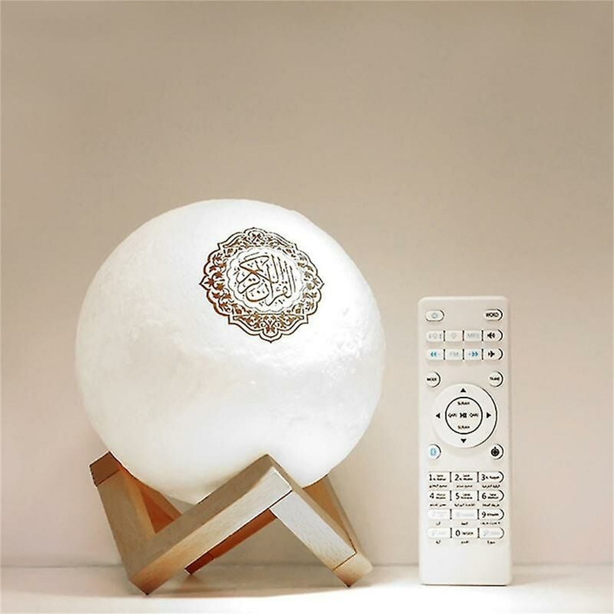 Mondförmige Lampe auf einem Holzständer mit arabischer Kalligraphie. Eine Fernbedienung ist in der Nähe.