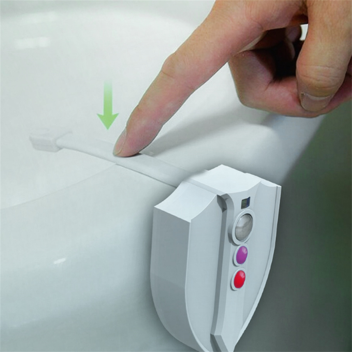 Eine Hand drückt einen Knopf auf einer weißen, schildförmigen Toilettensitzverriegelung. Es gibt drei Knöpfe.
