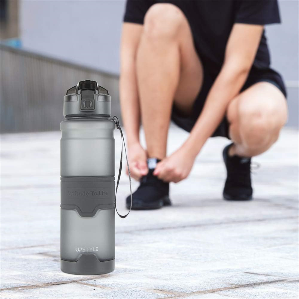 Eine Person, die sich die Schuhe bindet, mit einer grauen Wasserflasche im Vordergrund.
