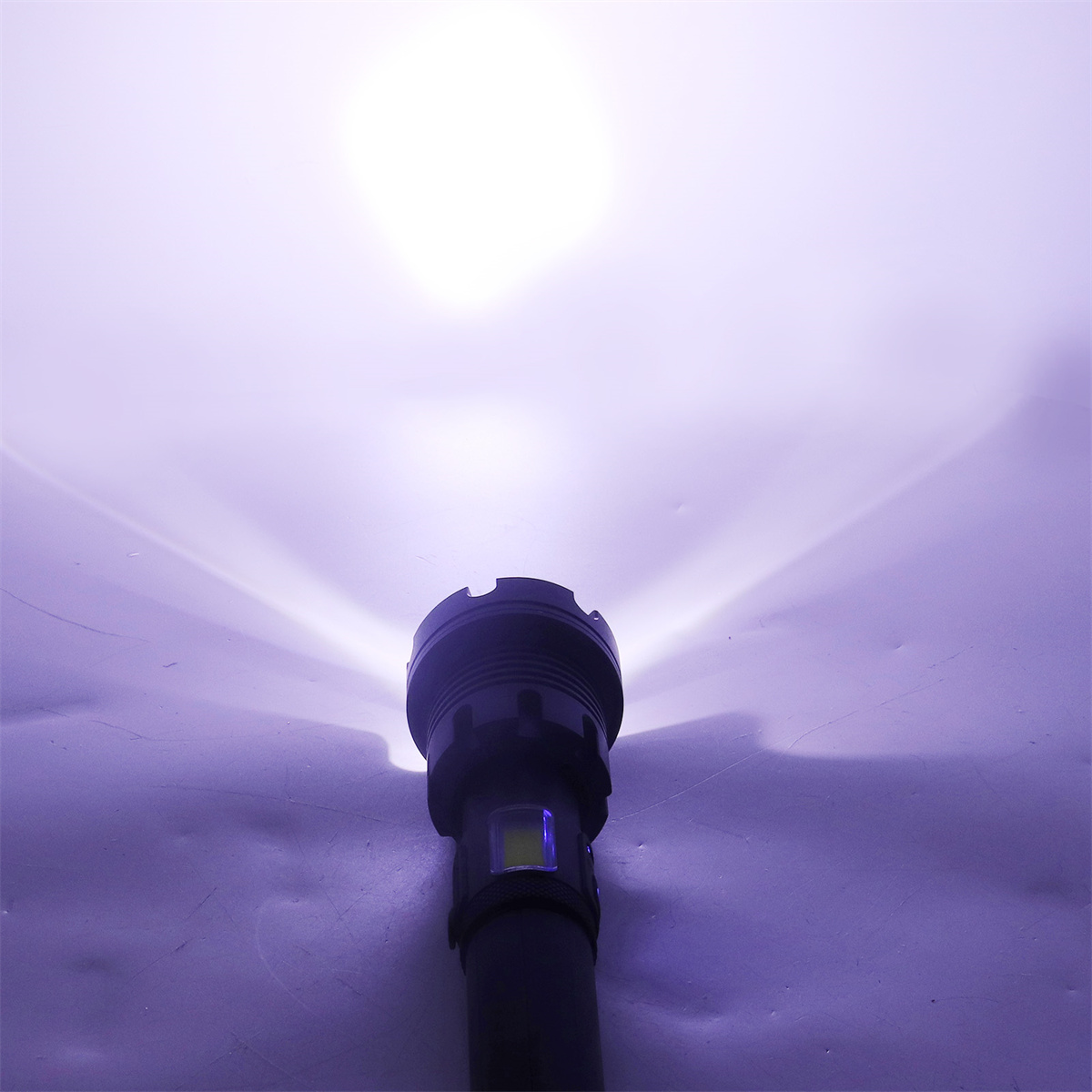 Eine Taschenlampe, die einen hellen weißen Strahl in einer dunklen Umgebung aussendet. Das Licht ist fokussiert und intensiv.