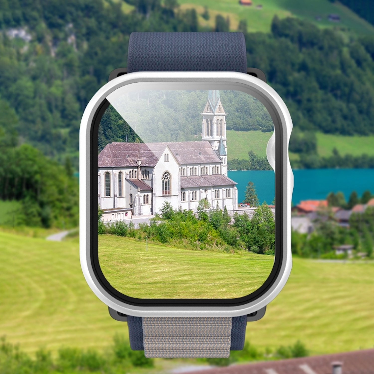 Smartwatch, das eine Kirche und einen See zeigt, umgeben von grünen Feldern und Bergen.
