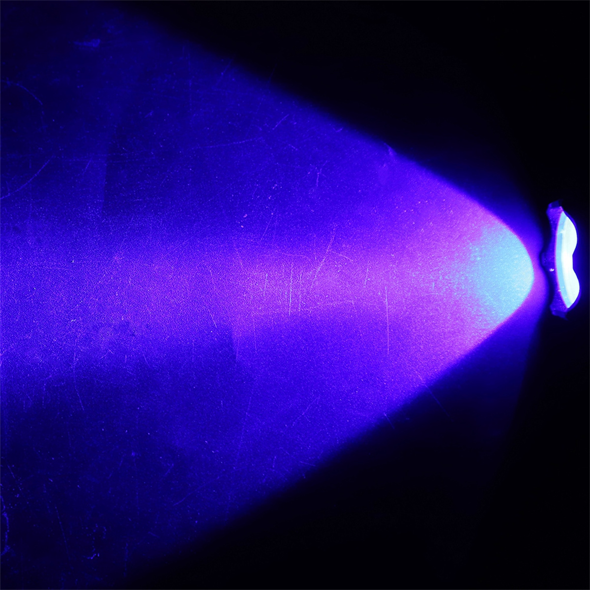 UV-Licht scheint auf eine Oberfläche. Lila Lichtstrahl, dunkler Hintergrund.