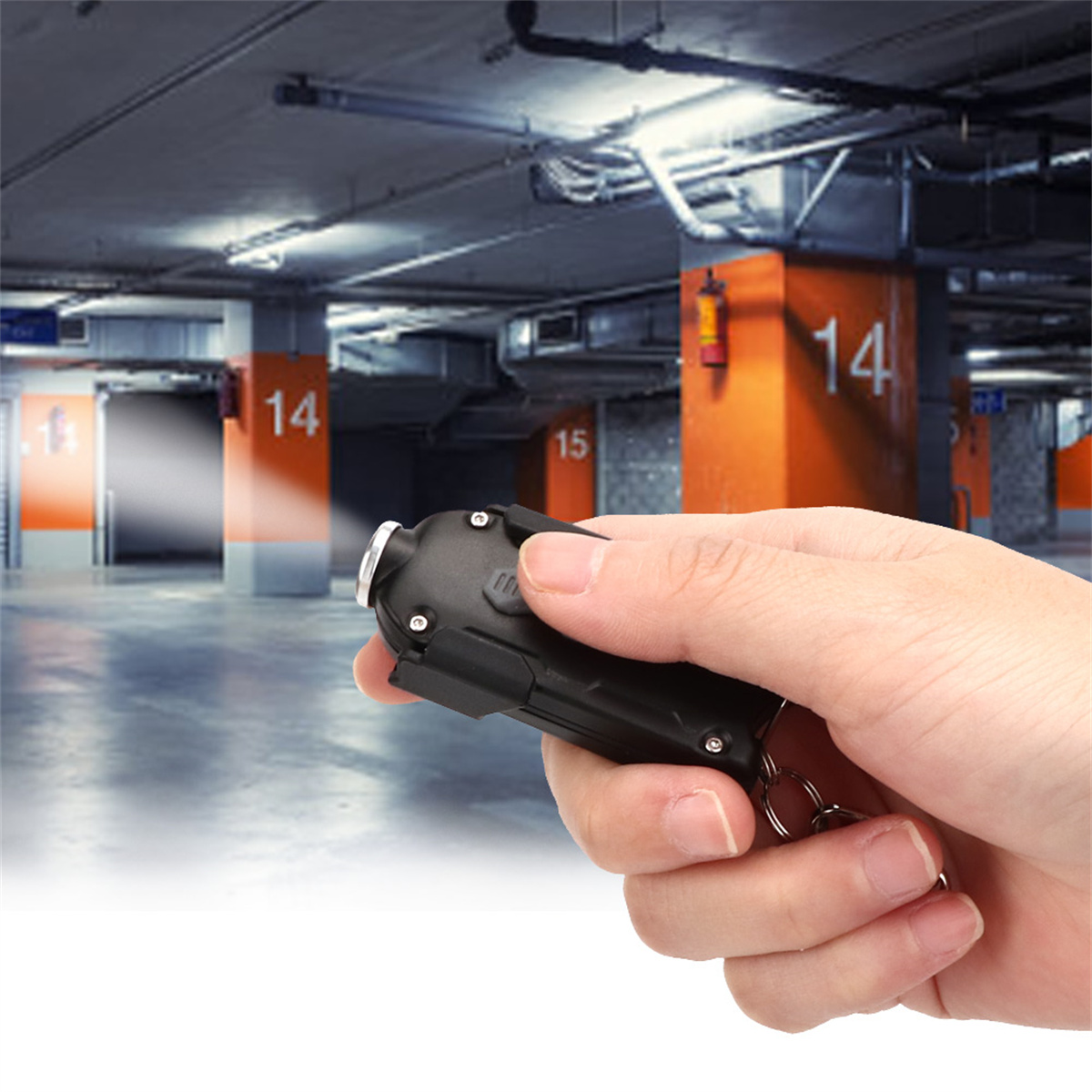 Eine Hand hält eine kleine schwarze Taschenlampe in einer Parkgarage, das Licht beleuchtet den Bereich.