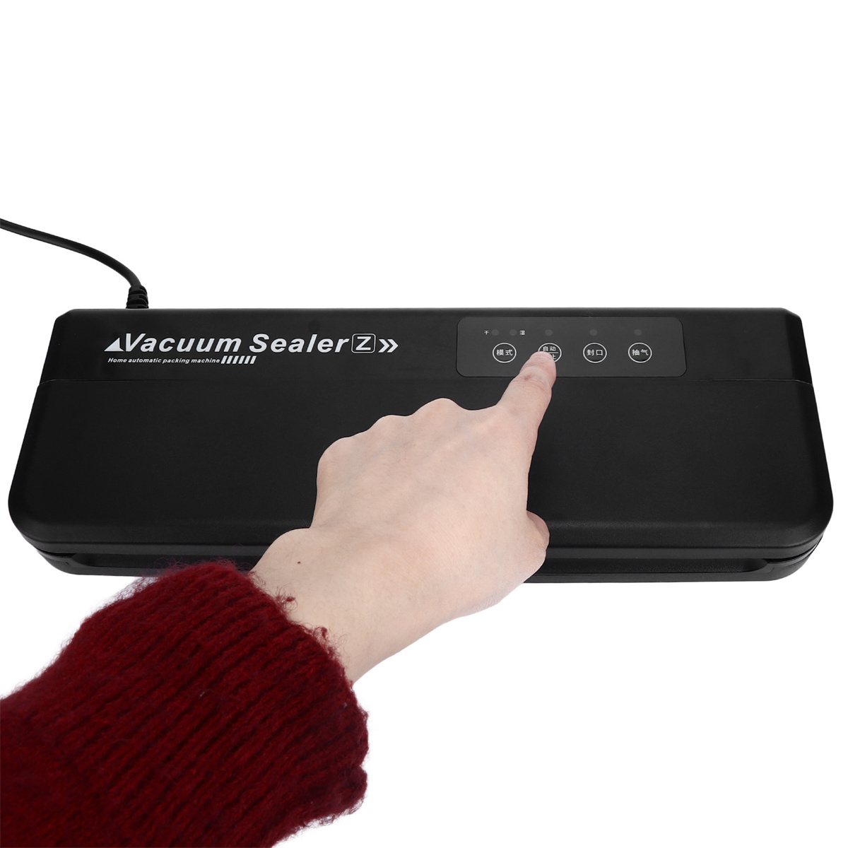 Hand drückt Knopf auf einem schwarzen Vakuumiergerät. Gerät hat Digitalanzeige, liegt auf weißer Oberfläche.