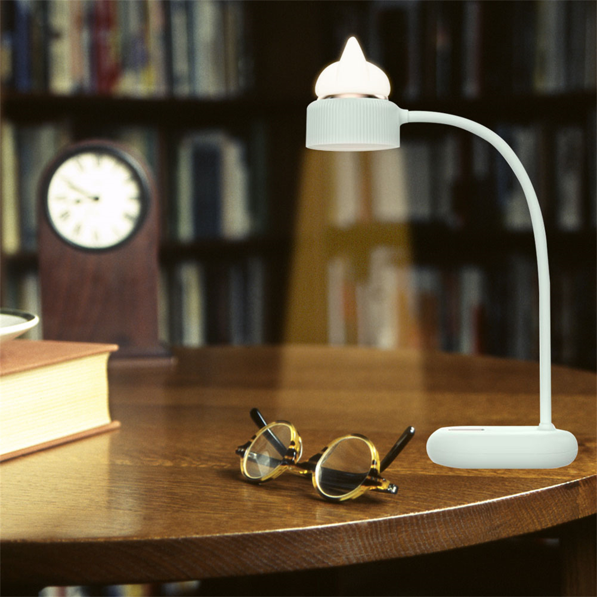 Eine weiße Schreibtischlampe mit kleinem Schirm und eine Brille mit schwarz-goldenem Rahmen.