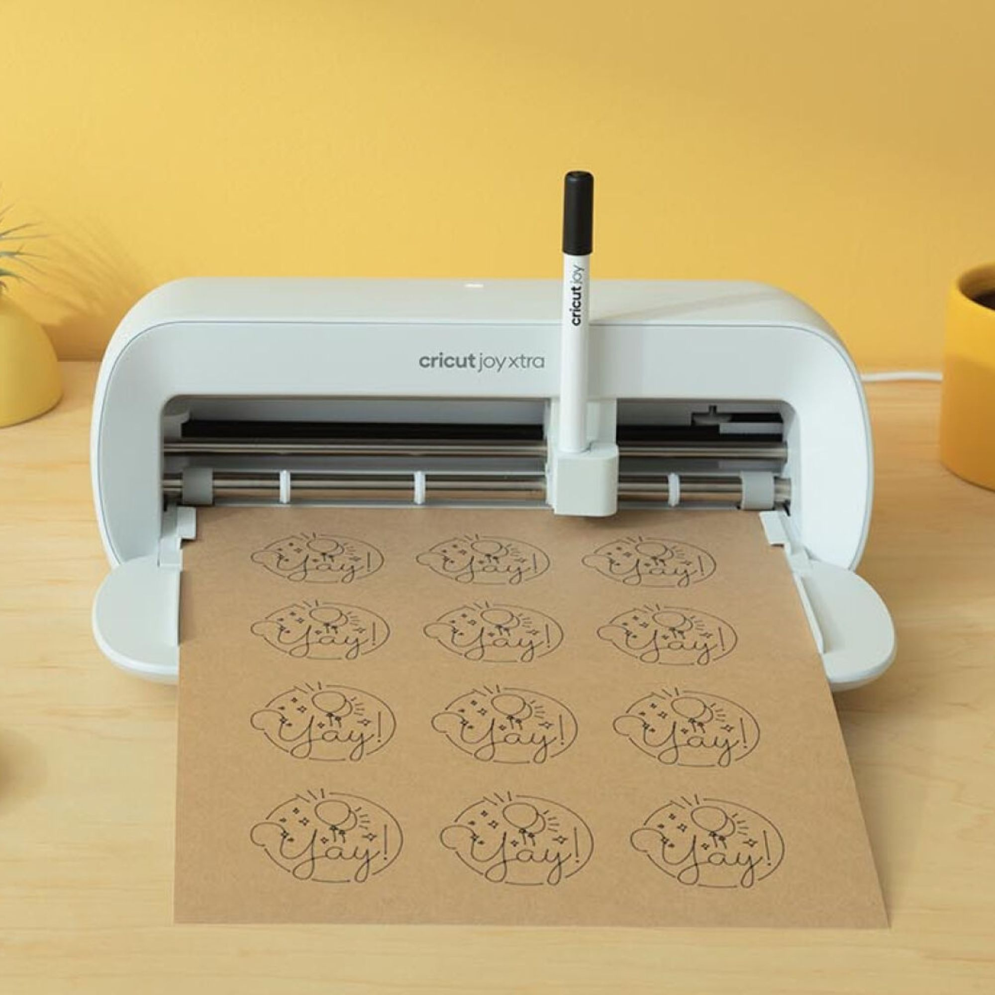 Una máquina Cricut Joy Xtra blanca imprimiendo diseños en papel marrón.