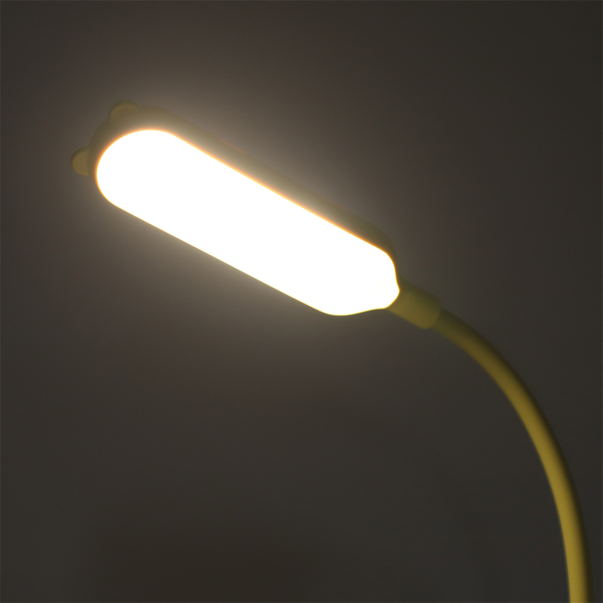 Eine gelbe Schreibtischlampe mit hellem Licht. Der Hintergrund ist dunkel.