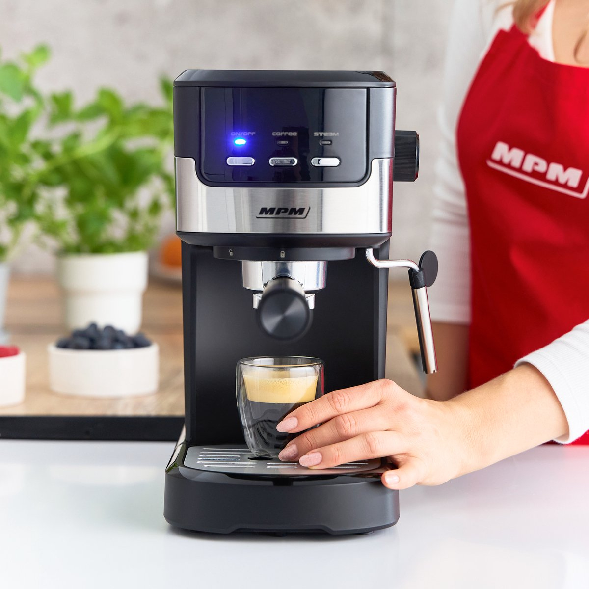 Una macchina per l'espresso con una tazza di caffè. Una mano versa il caffè nel bicchiere trasparente.