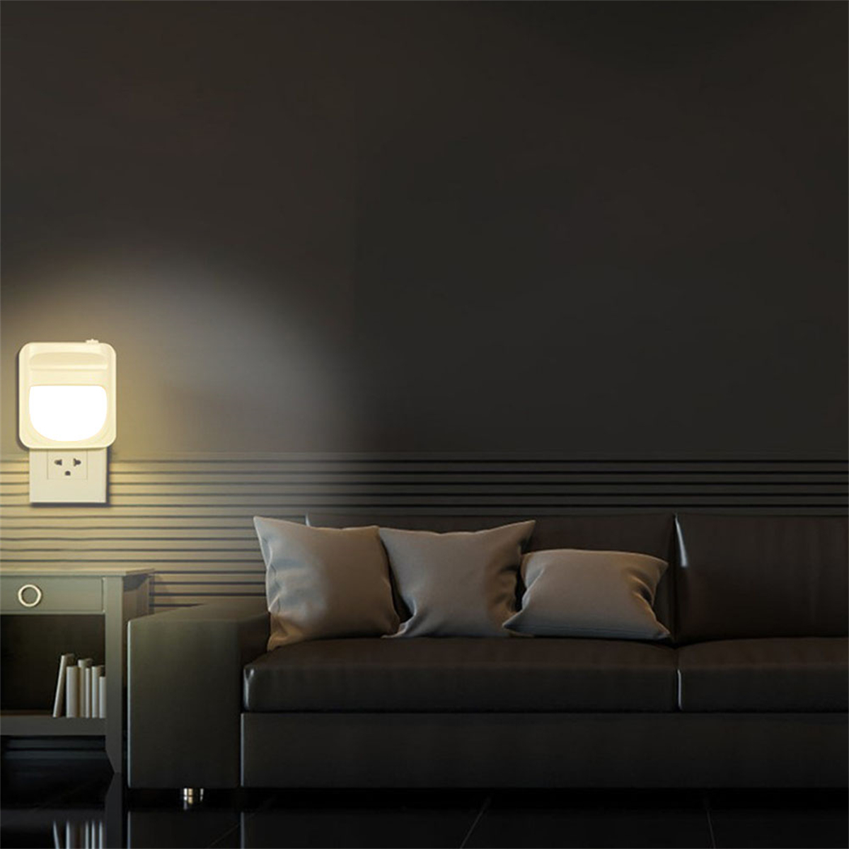 Ein Wandsteckdosen-Nachtlicht an einer Wand, über einem Sofa. Das Licht beleuchtet die Wand.