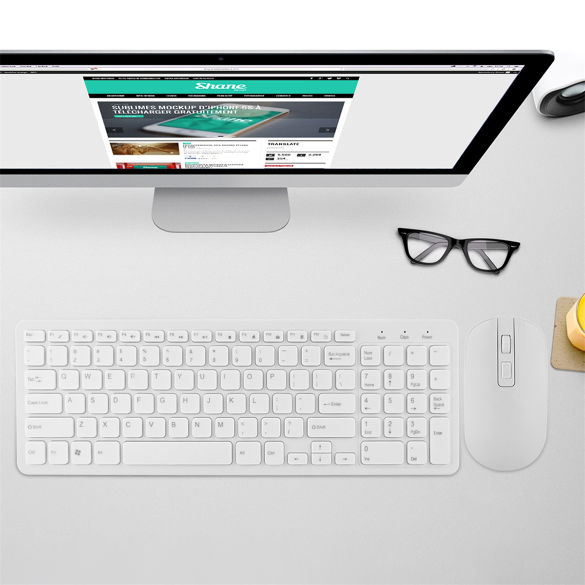 Weiße Tastatur und Maus auf einem Tisch. Ein Computerbildschirm im Hintergrund.