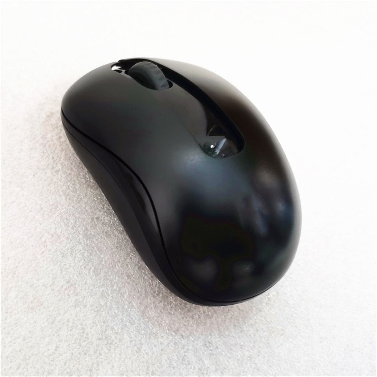 Schwarze kabellose Maus auf Weiß. Es hat ein Scrollrad und ein schlankes Design.