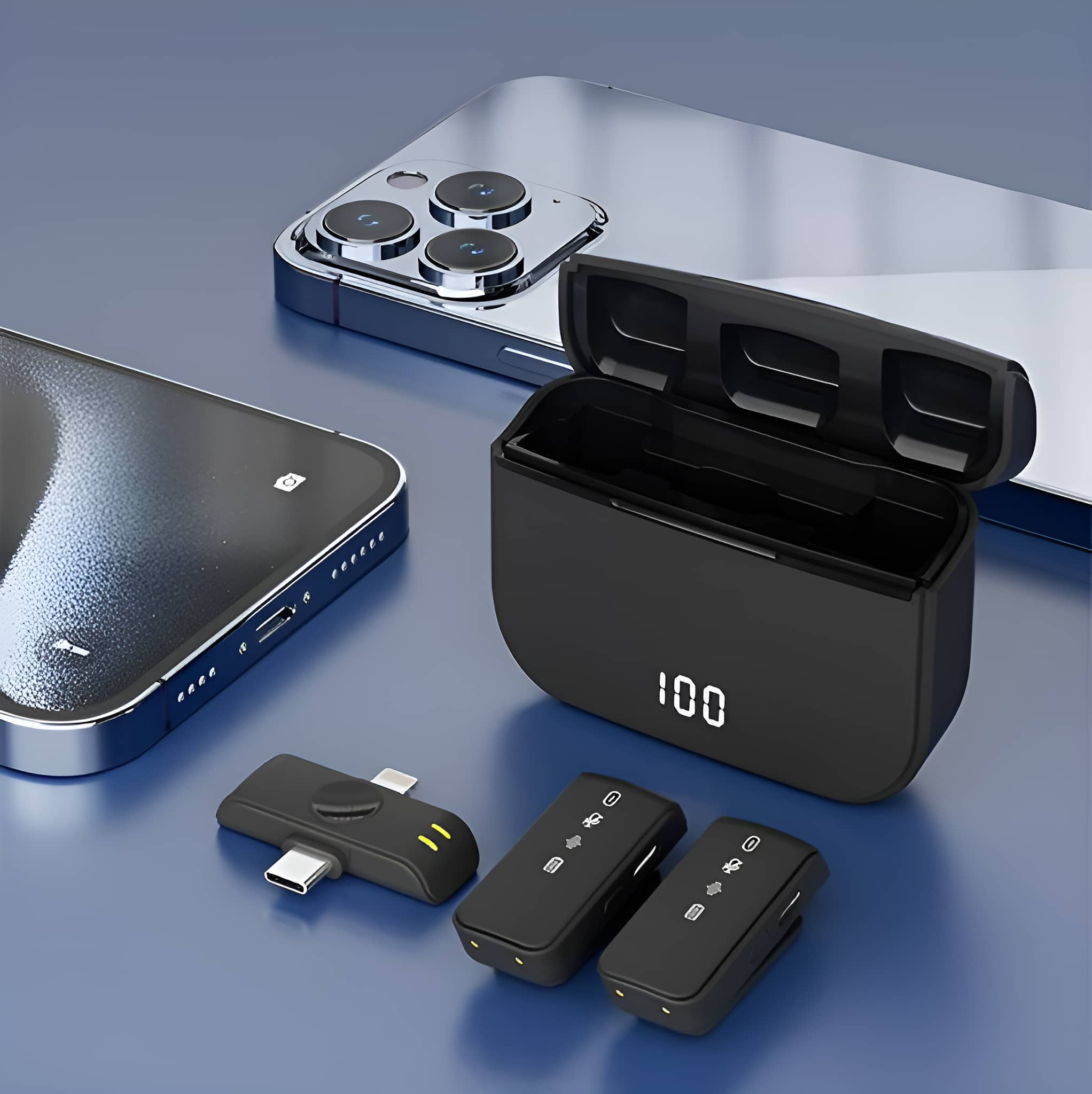 Schwarze, kabellose Mikrofone werden geladen, mit einem schwarzen Ladekoffer und einem Telefon auf einer blauen Oberfläche.