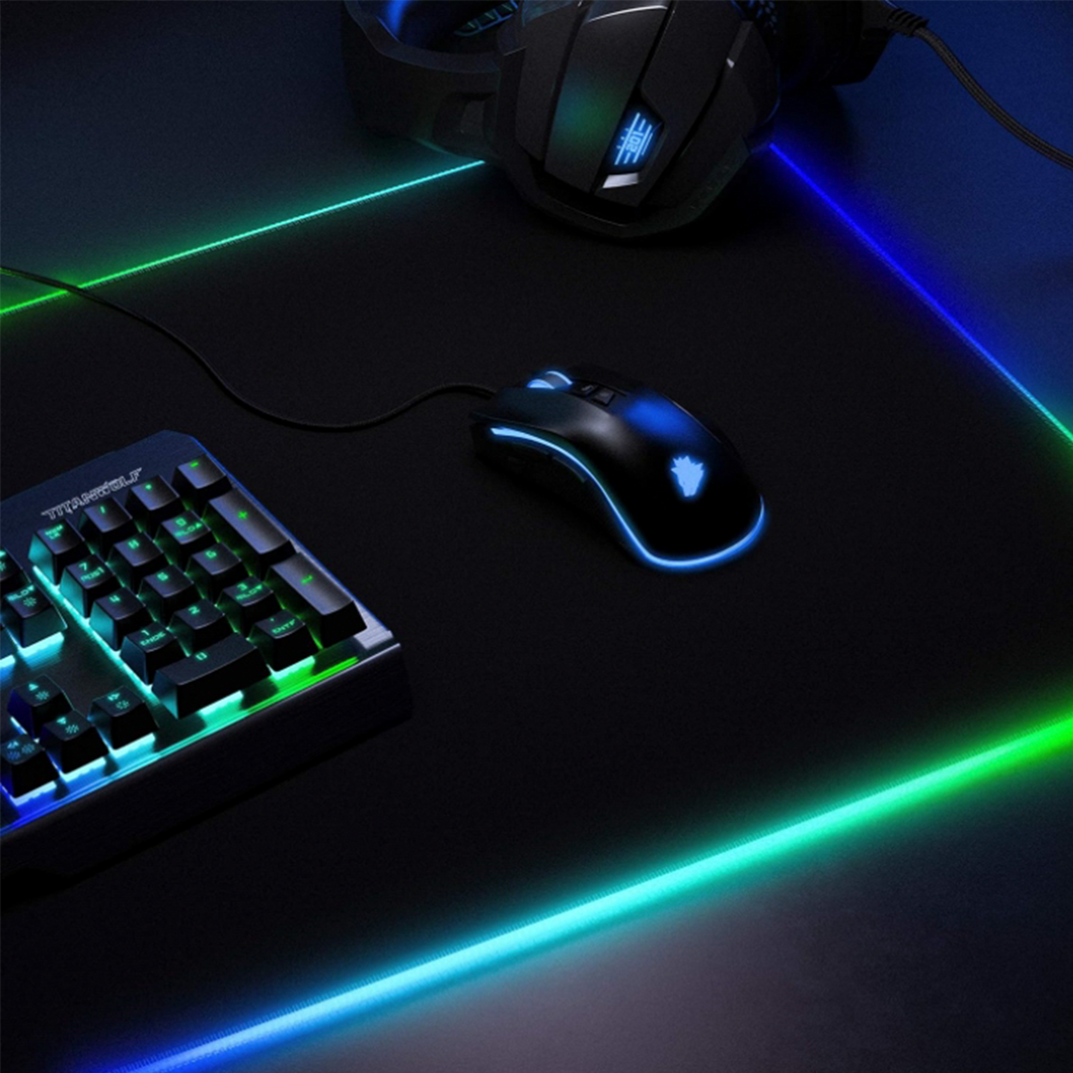 Gaming-Setup mit Tastatur, Maus und Mauspad mit Neonbeleuchtung. Szene hat einen dunklen Hintergrund.