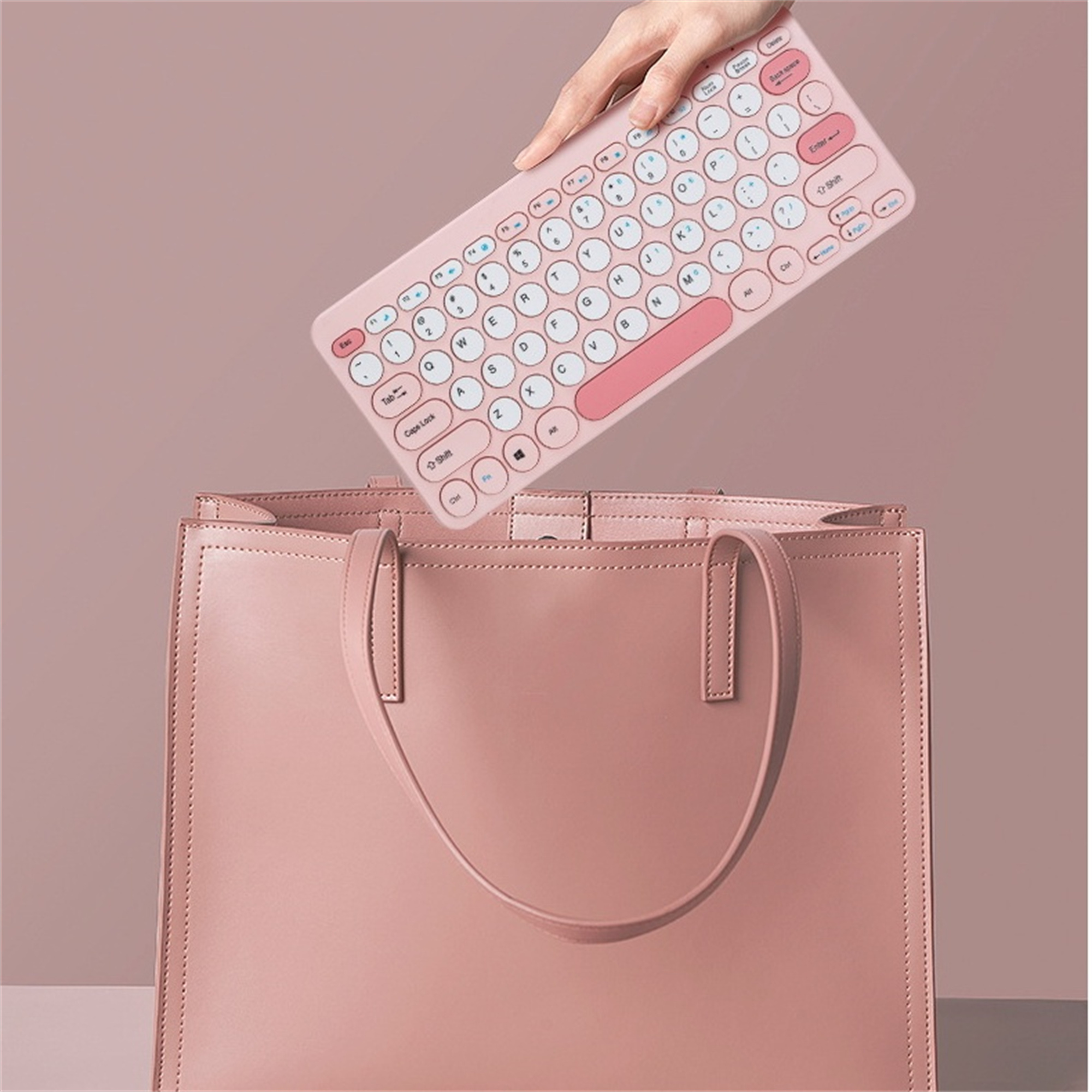 Eine rosa Tastatur wird in eine rosa Handtasche gelegt. Die Tastatur ist klein und kompakt.