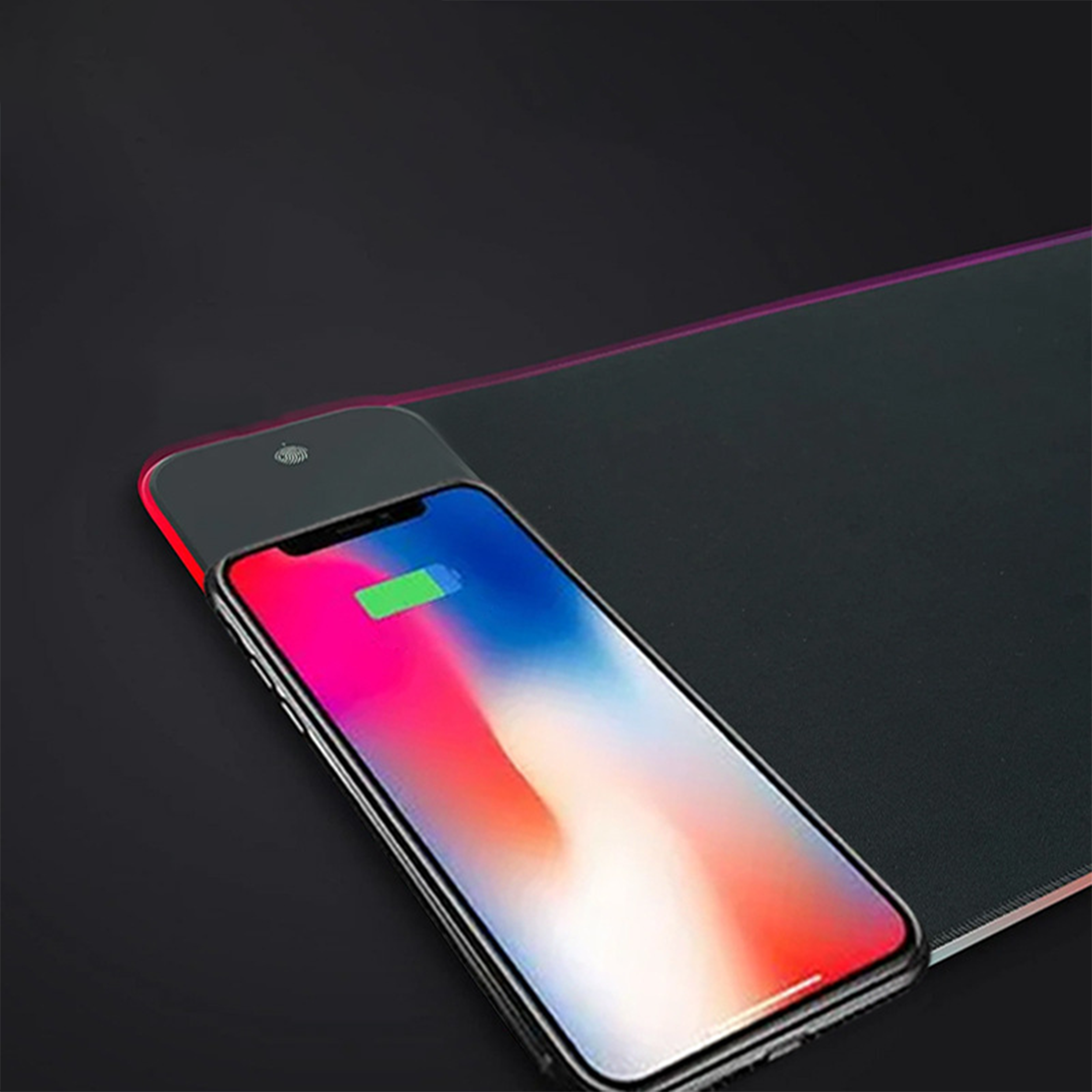 Ein Telefon, das auf einem schwarzen kabellosen Lade-Mauspad geladen wird. Rote und schwarze Akzente.