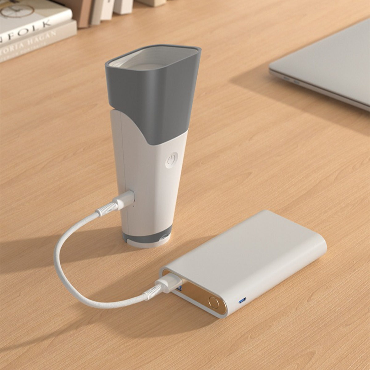 Weißer und grauer tragbarer Luftbefeuchter mit einer Powerbank. USB-Kabel verbindet die beiden. Holztisch.
