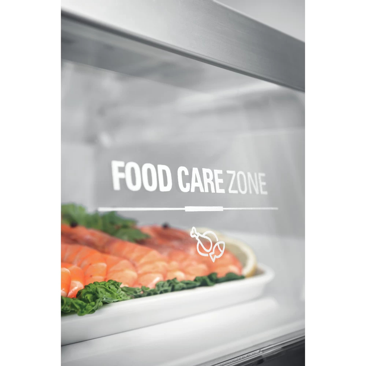 Dentro de un refrigerador, con la etiqueta Food Care Zone y una bandeja de comida.