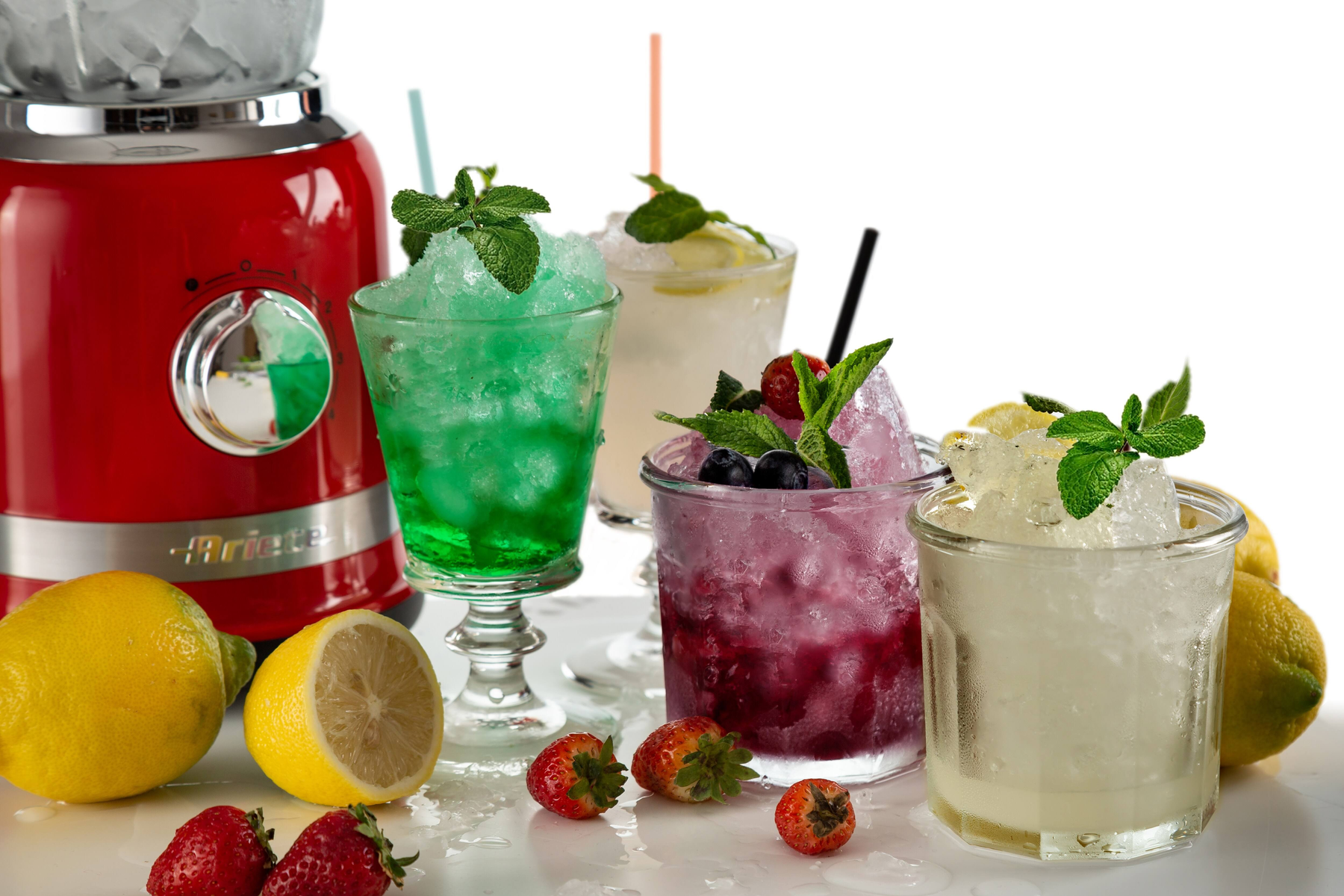 Cocktails mit Crushed Ice. Ein roter Mixer im Hintergrund. Erdbeeren und Zitronen sind vorhanden.