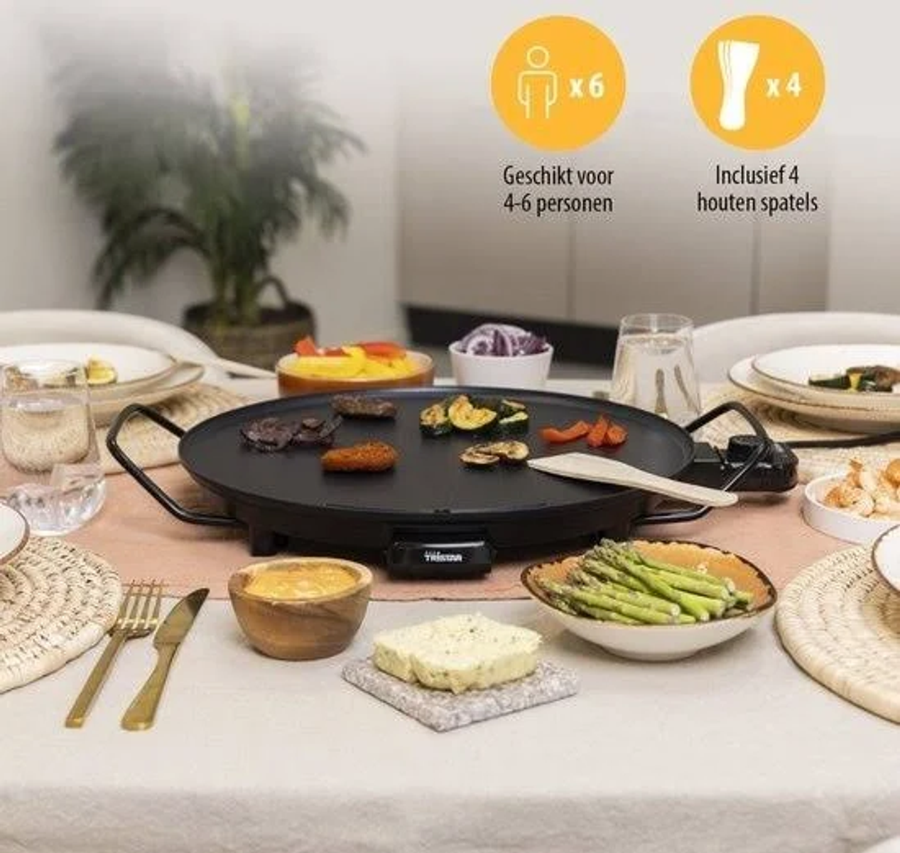 Nakrycie stołu z grillem do raclette, jedzeniem i sztućcami.