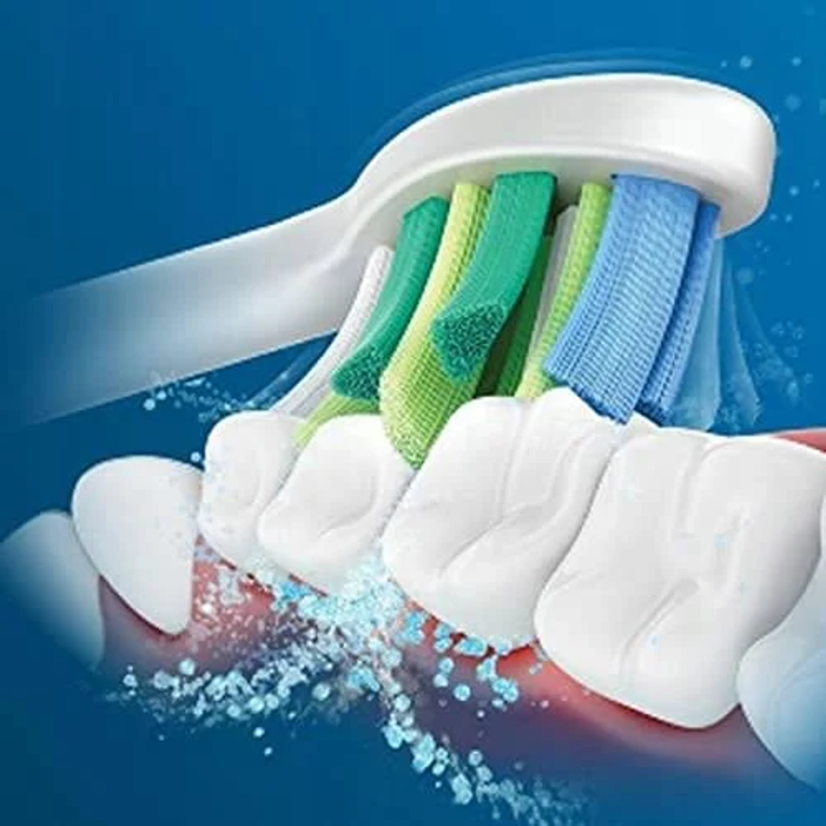 Zbliżenie szczoteczki do zębów czyszczącej zęby niebieskim i zielonym włosiem.