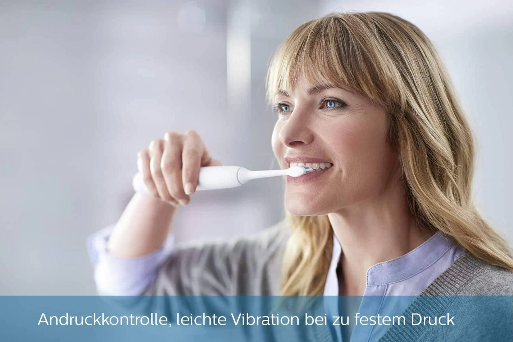 Kobieta myje zęby białą szczoteczką elektryczną. Tekst poniżej brzmi: Kontrola nacisku.