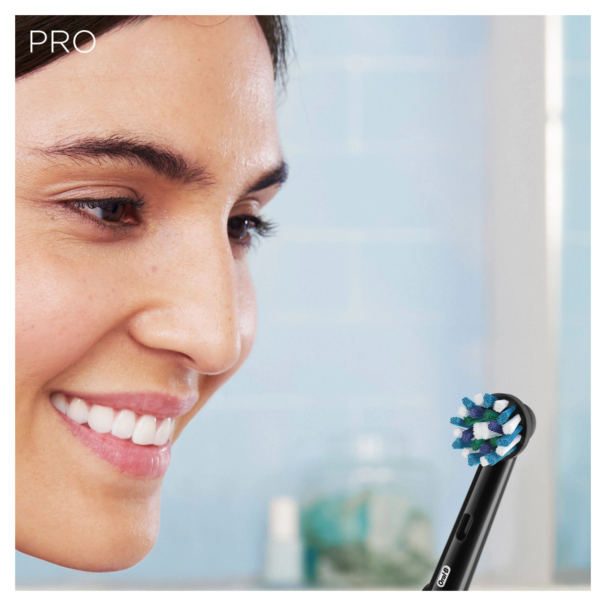 Primer plano de una mujer sonriendo, con un cepillo de dientes en la boca, mostrando dientes sanos.