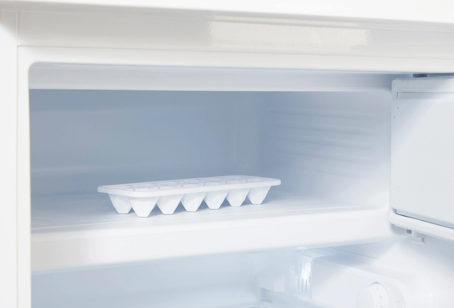 Refrigerador blanco abierto con cubitera en un estante. Interior vacío con un tono azul claro.