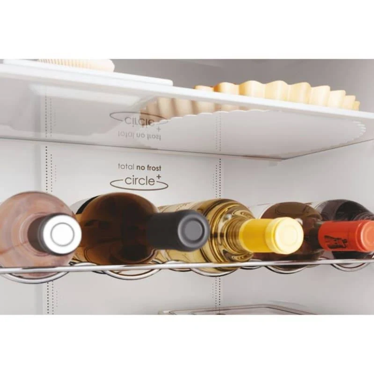 Wnętrze lodówki z butelkami wina na półkach, otoczone białym wnętrzem.