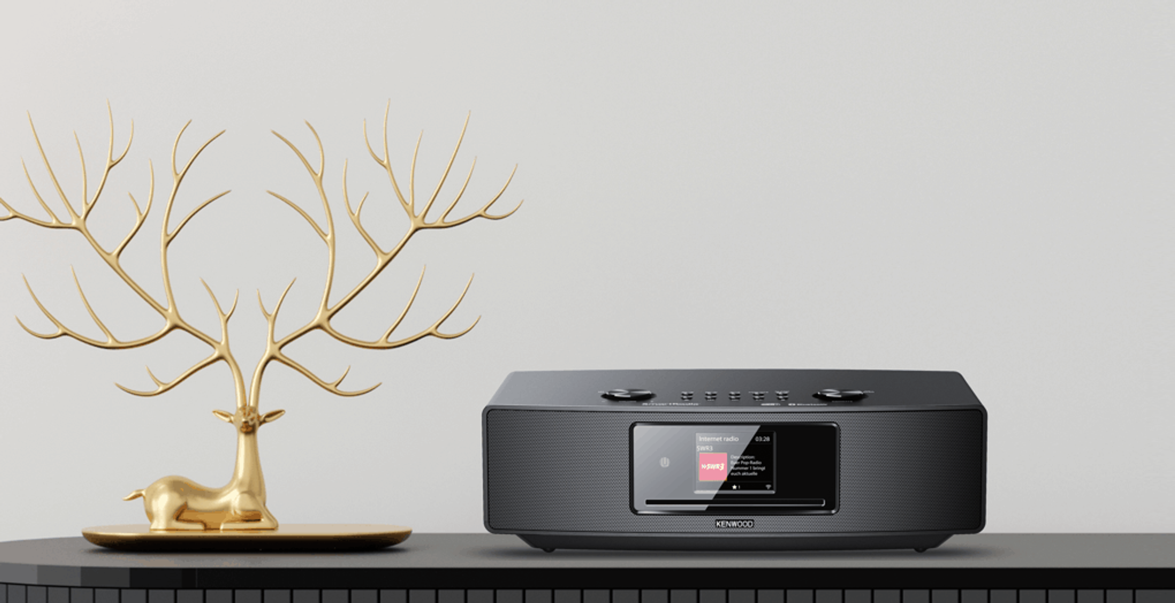Zwart Kenwood audiosysteem met een scherm, gouden hert en een plank.