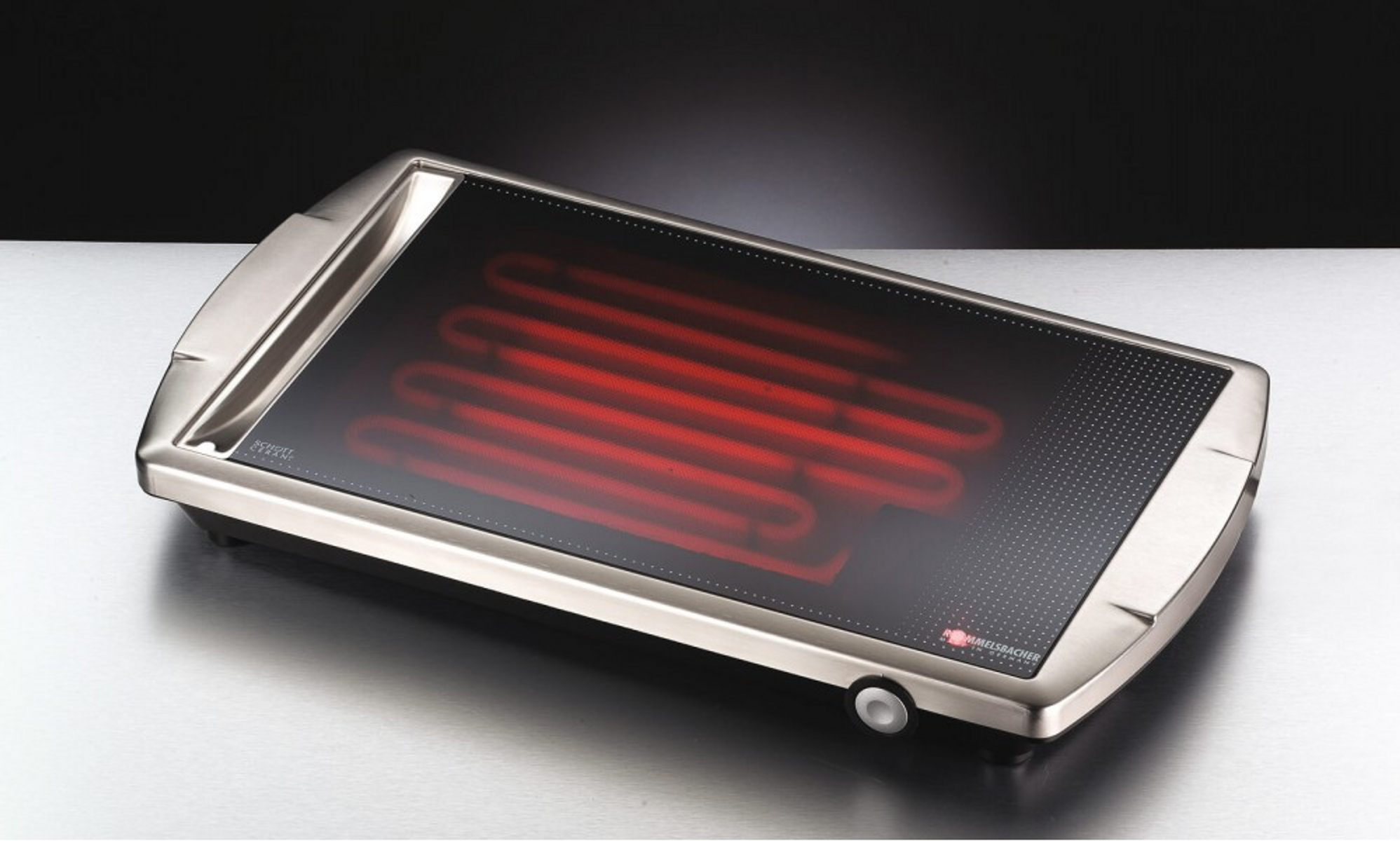 Ein silberner Elektrogrill mit schwarzer Kochfläche. Rote Heizelemente sind durch das Glas sichtbar.