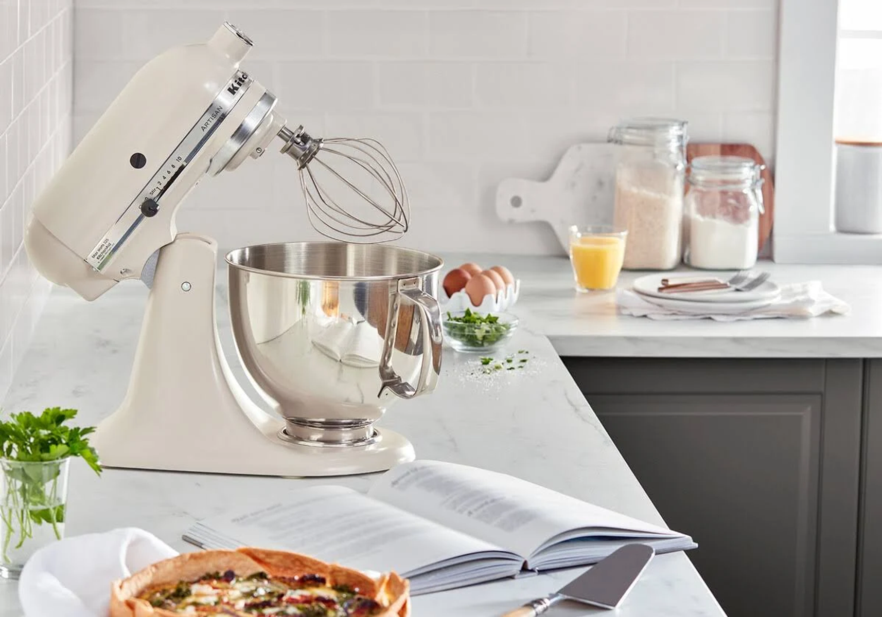 Tezgahta malzemelerle KitchenAid mikser. Tezgahta bir pasta var.