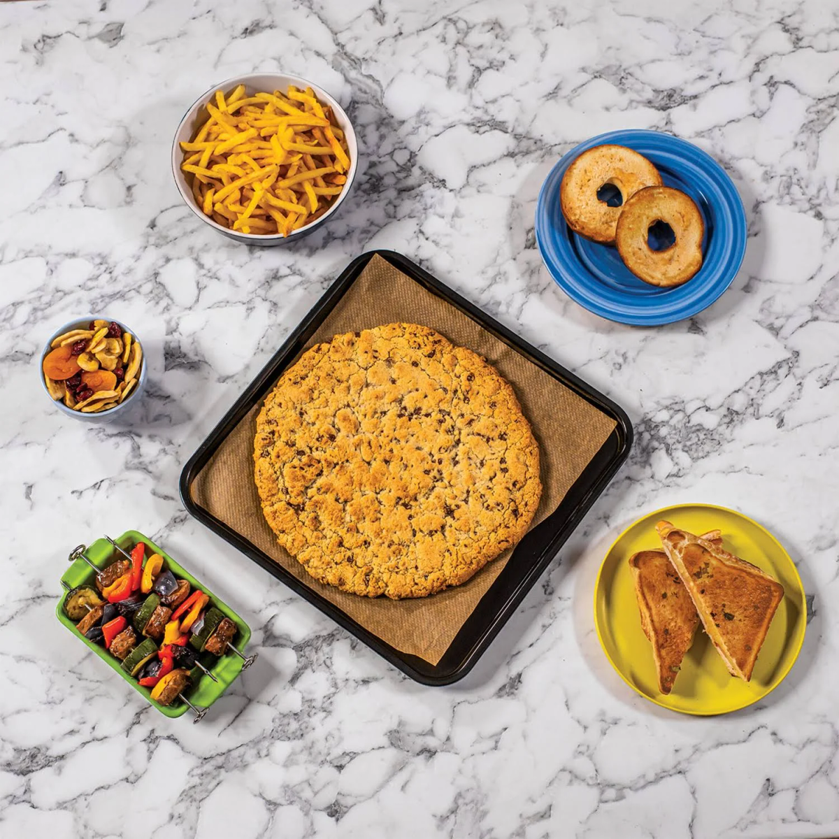 Alimentos sobre una superficie de mármol: papas fritas, bagels, pizza, sándwich a la parrilla y kebab.