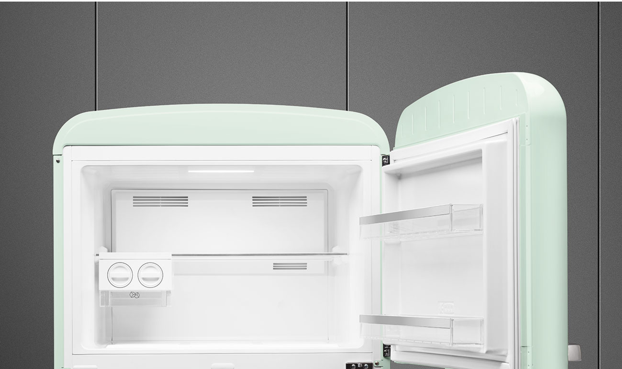 Refrigerador retro verde menta abierto. El interior es blanco con estantes, cajones y un congelador.