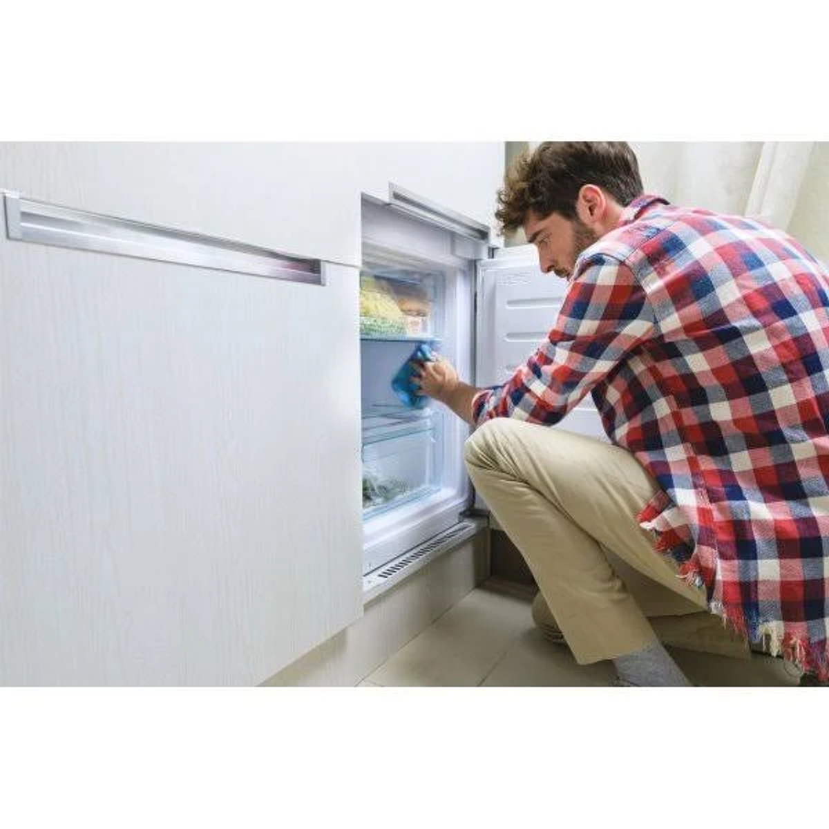 Mężczyzna czyści wnętrze białej lodówki.