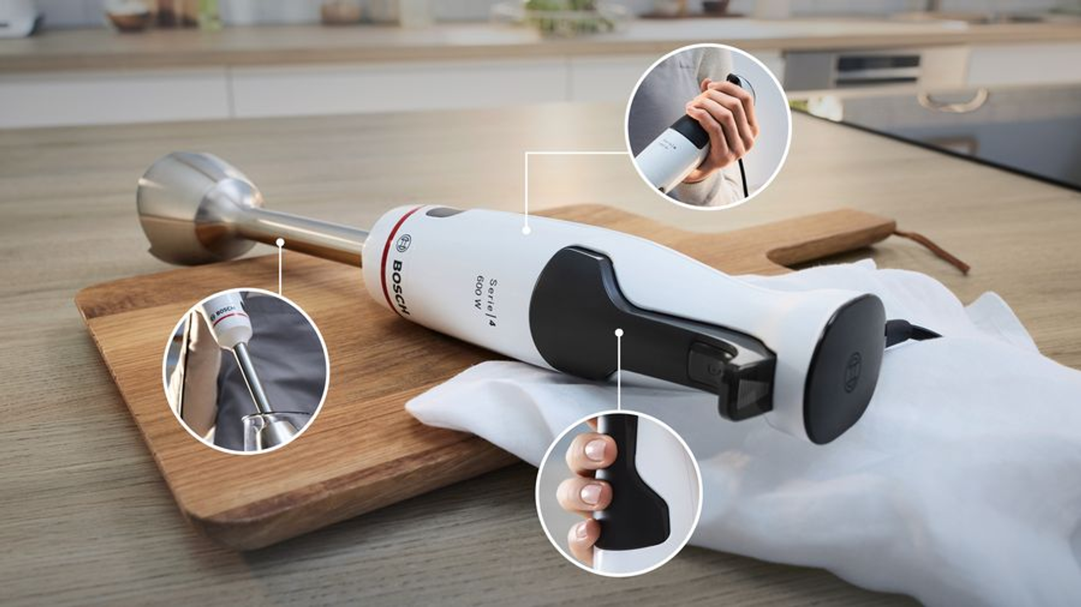 Biały blender ręczny Bosch z przystawkami na desce do krojenia.