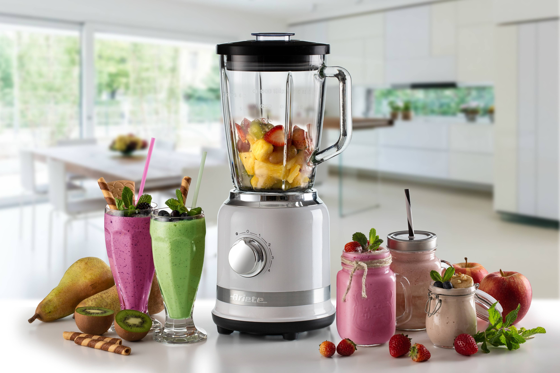 Blender met fruit. Smoothies in glazen met rietjes. Keuken achtergrond.