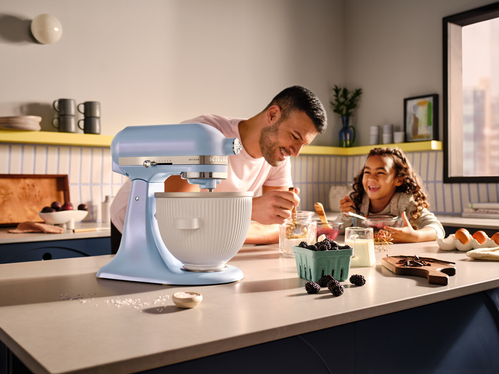 Un uomo e un bambino usano un frullatore KitchenAid blu.