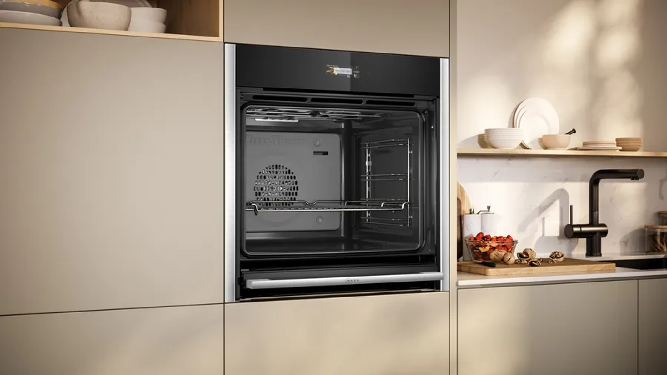 In einen Küchenschrank eingebauter Backofen, offene Tür. Küchenumgebung mit verschiedenen Elementen.