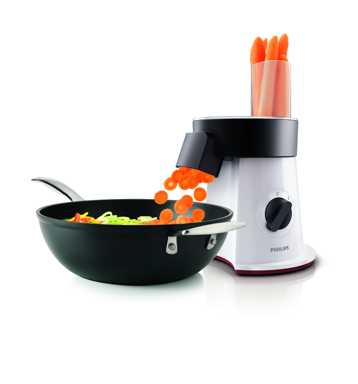 White and black food processor with carrots being sliced into a pan.