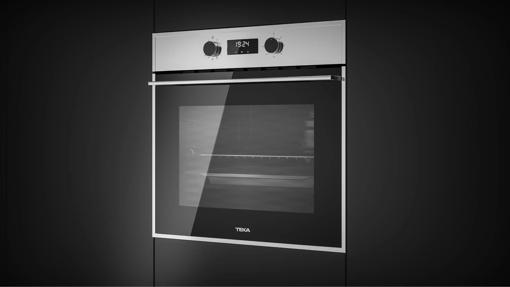 Un horno de acero inoxidable empotrado en una pared oscura, mostrando la hora 19:24.
