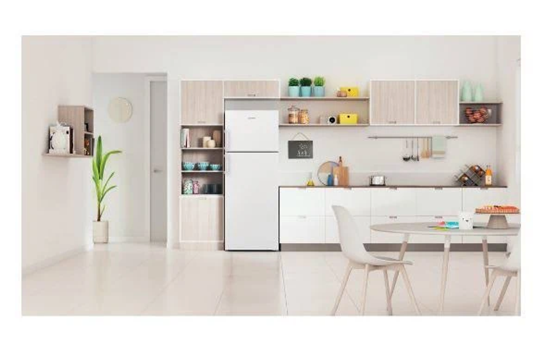 Cocina blanca con armarios, electrodomésticos y una mesa redonda. Hay plantas y decoración.