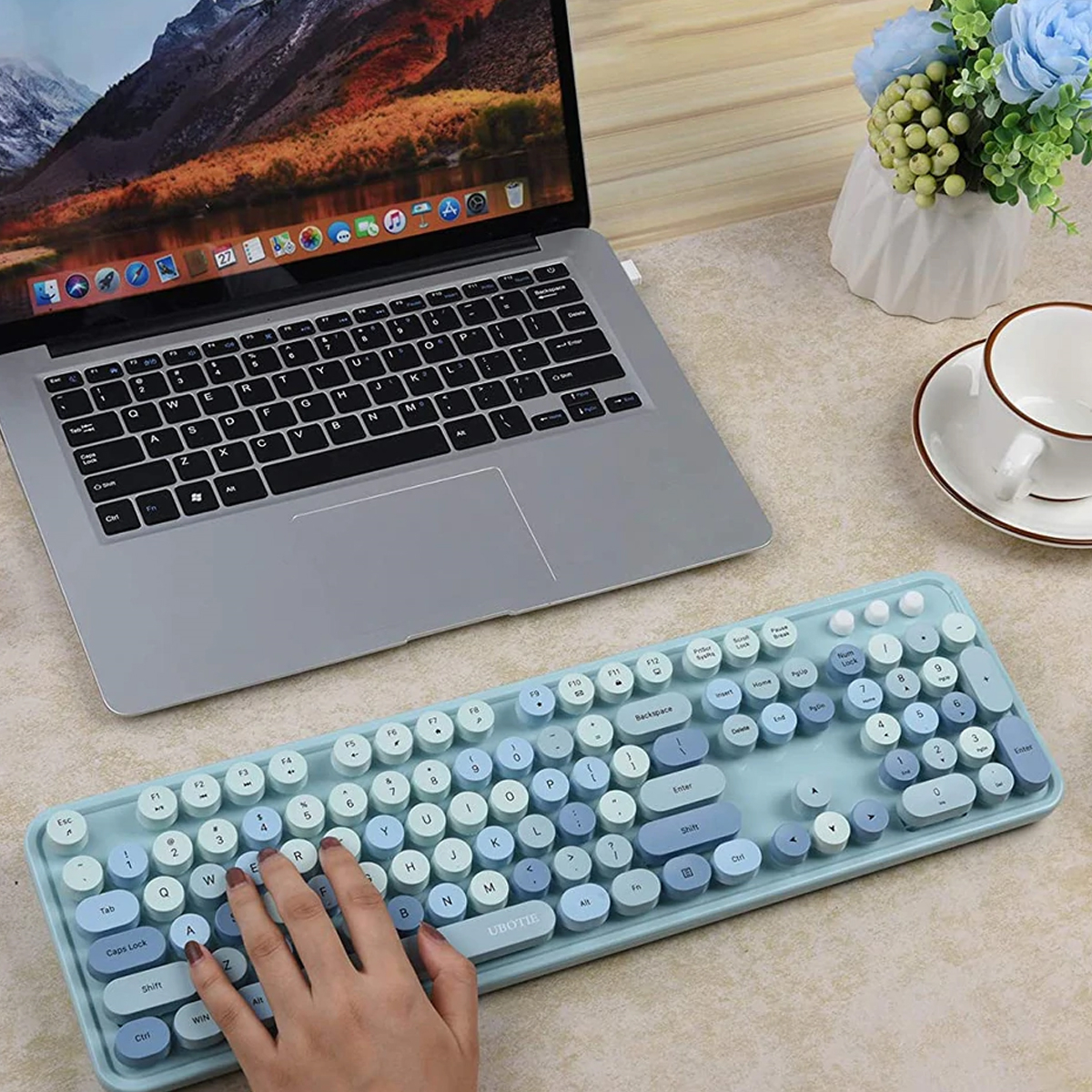 Eine hellblaue Tastatur mit weißen und blauen runden Tasten auf einem Holzschreibtisch.