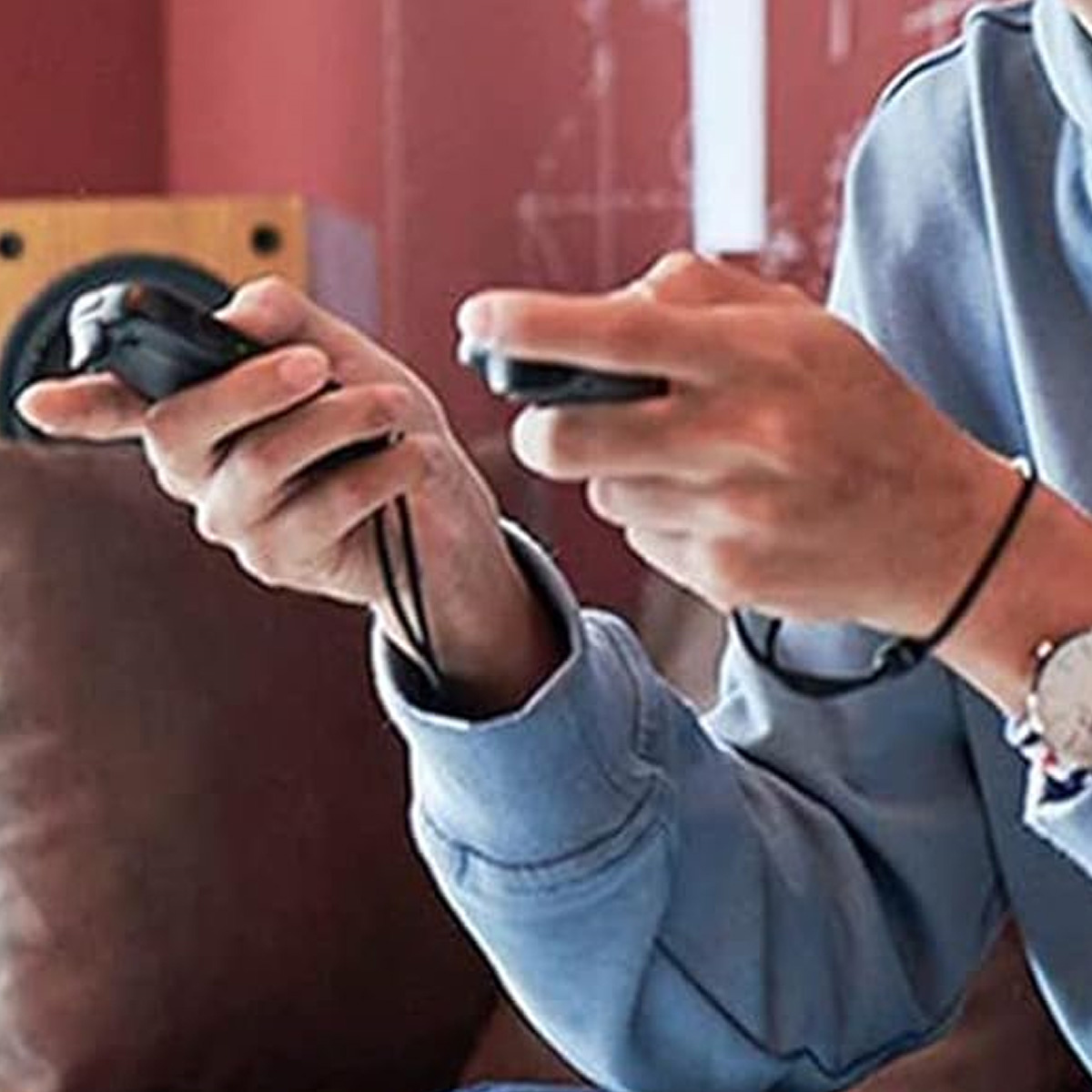 Eine Person hält zwei Gamecontroller. Die Person trägt einen blauen Sweatshirt.