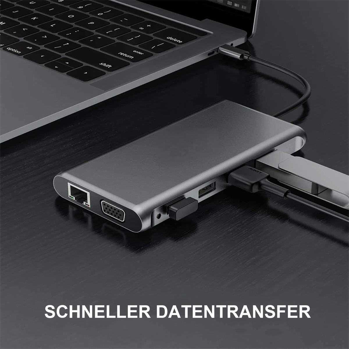 Silberner Hub, an einen Laptop angeschlossen, mit mehreren Anschlüssen, auf einem dunklen Holzschreibtisch.